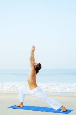 Mat 'in atletik adamı plajda yoga yapıyor.