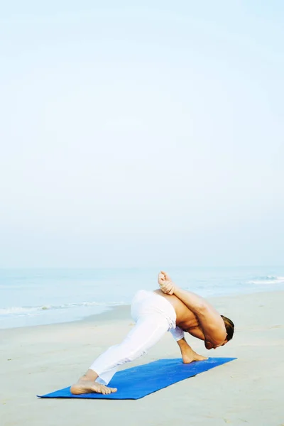 Mat 'in atletik adamı plajda yoga yapıyor. — Stok fotoğraf