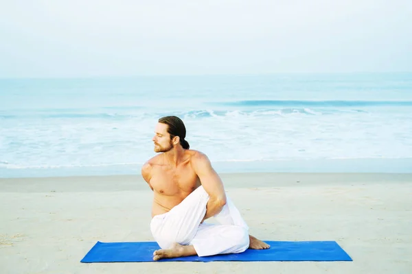 Athletic Man på Mat gör Yoga på stranden Royaltyfria Stockfoton