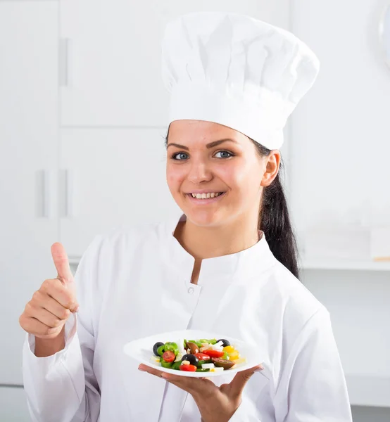 Brunette meisje chef-kok en bord met salade — Stockfoto