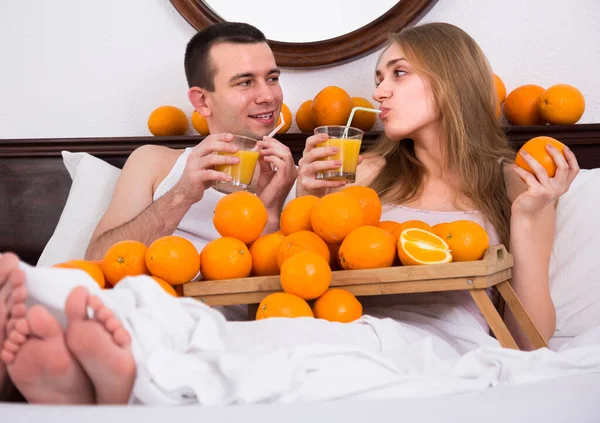 Coppia a letto con frutta arancione — Foto Stock