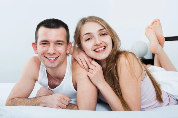 Positive young happy adults lying in family bed — Stock Photo, Image