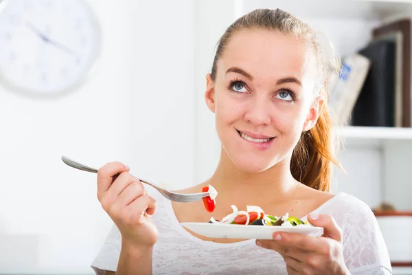 Giovane donna che mangia insalata in cucina — Foto Stock