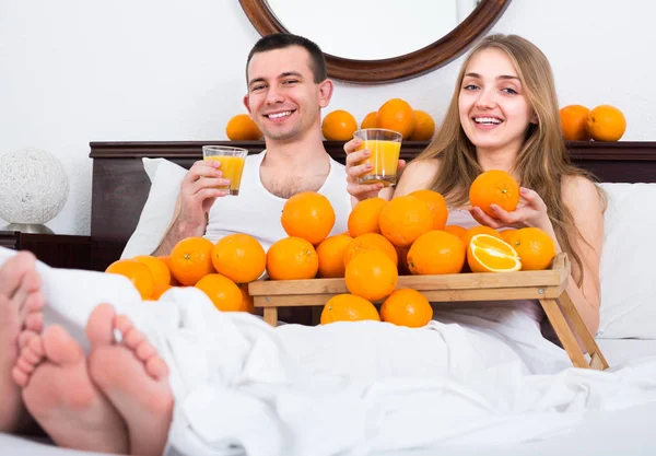 Coppia a letto con frutta arancione — Foto Stock