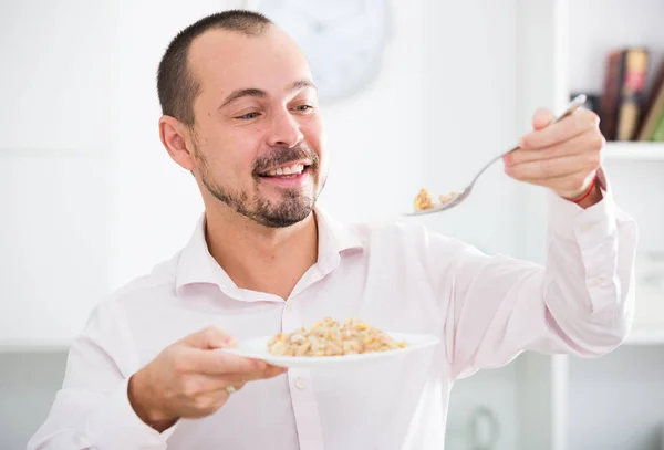 Positive young man eating porridge — Stock Photo, Image