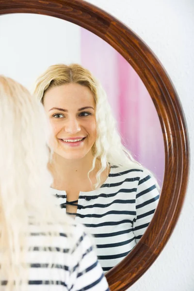 Nettes Mädchen sieht sich im Spiegel drinnen an — Stockfoto