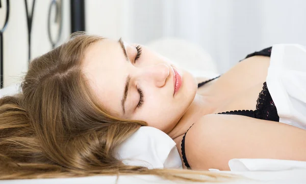 Vrouw liggend in bed onder laken met gesloten ogen — Stockfoto