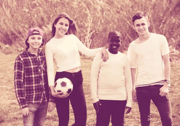 Κορίτσι και τρία αγόρια παίζουν ποδόσφαιρο στο πάρκο άνοιξη και χαμογελώντας — Φωτογραφία Αρχείου