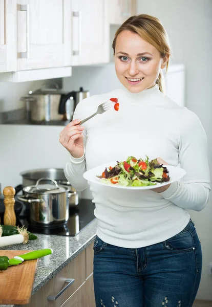 Menina feliz com salada de legumes na cozinha — Fotografia de Stock