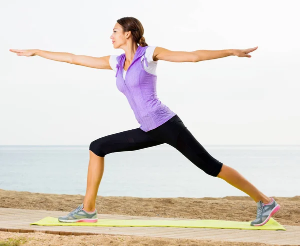 Woman practising yoga poses standing on beach — Stock Photo, Image