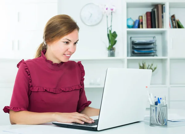 Junge attraktive Mitarbeiterin tippt auf tragbarem Computer — Stockfoto