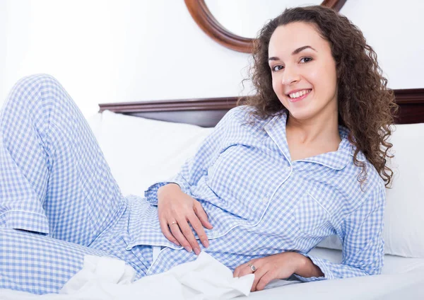 Brunette female lounging in bed and smiling — Stock Photo, Image