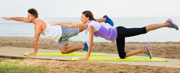 Joven pareja formación yoga poses sentado en la playa — Foto de Stock