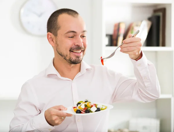 Smiling man looking at greek salad — Stock Photo, Image