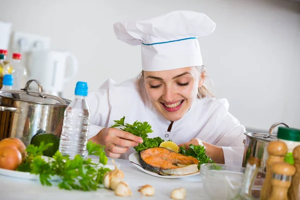 Young female chief with fried fish on plate — Stock Photo, Image