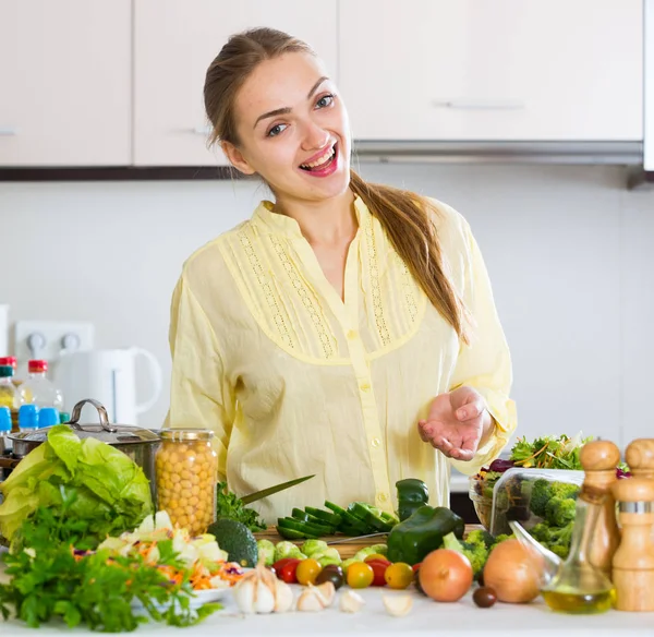 Happy young woman in yellow blouse cooking veggies — Stock Photo, Image