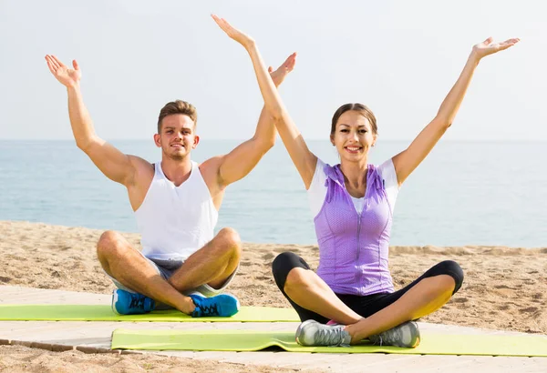 Paar im Schneidersitz praktiziert morgens Yoga am Strand — Stockfoto