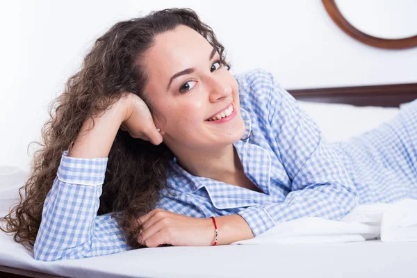 Kudrnaté vlasy mladá žena relaxační v posteli — Stock fotografie