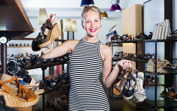 Frau steht in Boutique und hat viele Schuhe — Stockfoto