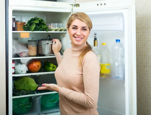 Satisfeito dona de casa perto da geladeira cheia — Fotografia de Stock