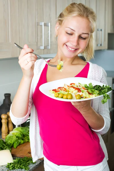 Девушка наслаждается свежим салатом на кухне — стоковое фото
