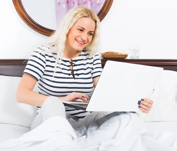 Молодая женщина с ноутбуком в постели — стоковое фото