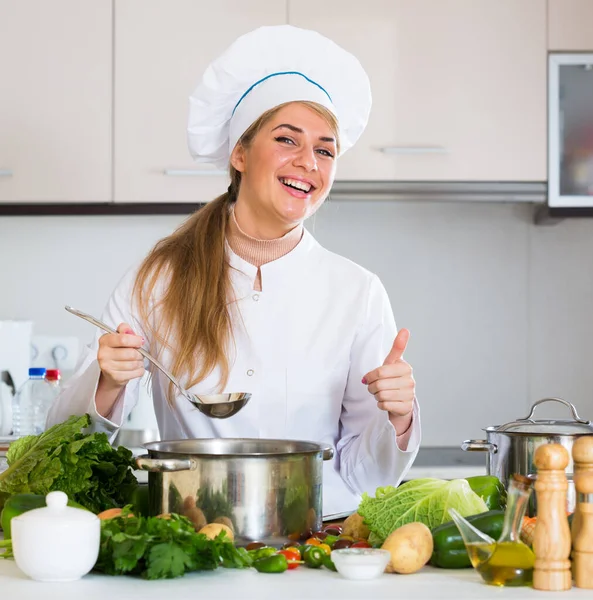 Mutlu kadın aşçı sebze hazırlıyor ve evde gülümsüyor. — Stok fotoğraf