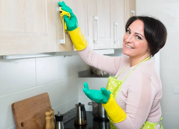 Dona de casa removendo manchas de armários na cozinha — Fotografia de Stock