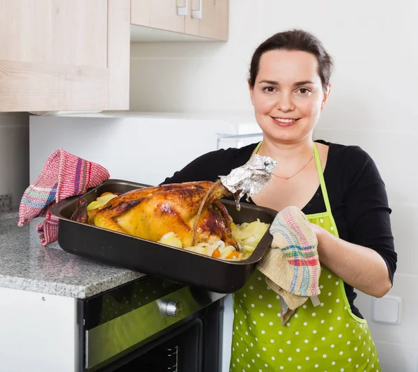 Jonge vrouw roostert haan als avondeten — Stockfoto