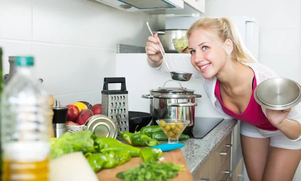 Adult girl standing at kitchen and cooking soup — 스톡 사진