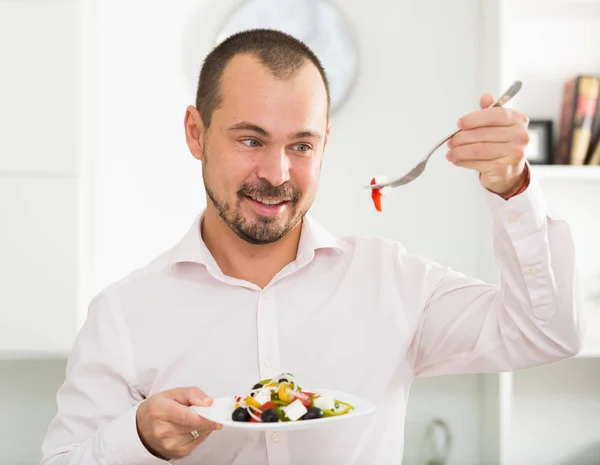 Smiling man looking at greek salad — Stock Photo, Image