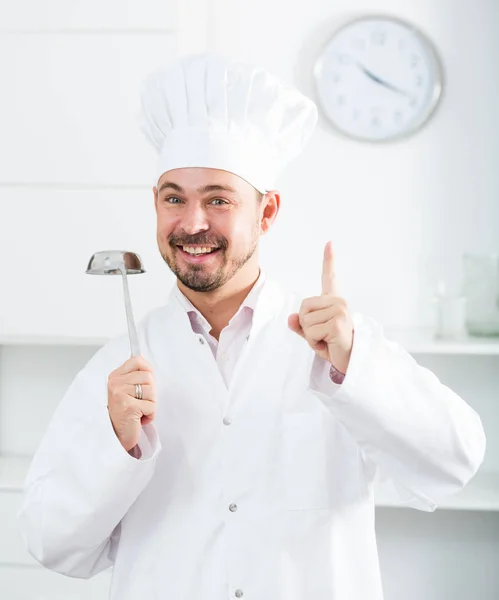 Positivo joven cocinero sosteniendo cucharón de sopa — Foto de Stock
