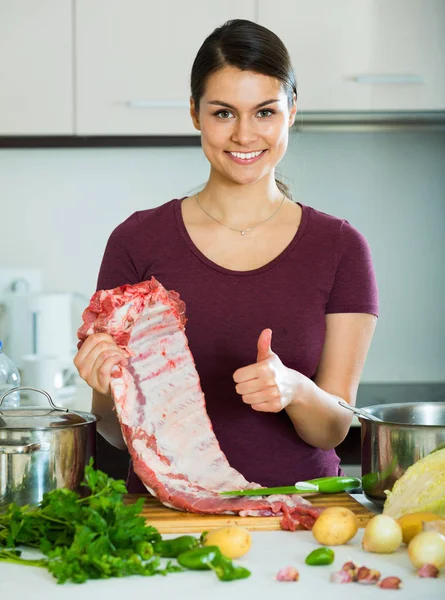 Счастливая молодая женщина готовит мясо — стоковое фото