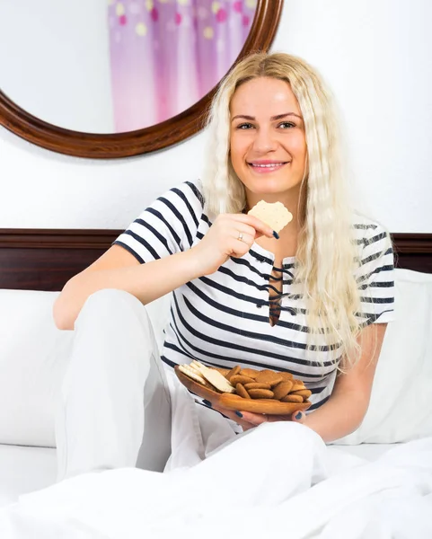 Slim fêmea comer biscoitos na cama — Fotografia de Stock