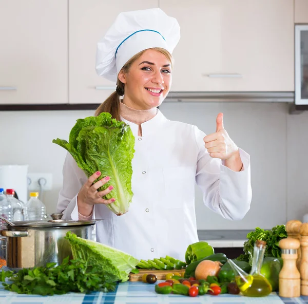 Молодой шеф-повар со свежим салатом позирует на кухне — стоковое фото