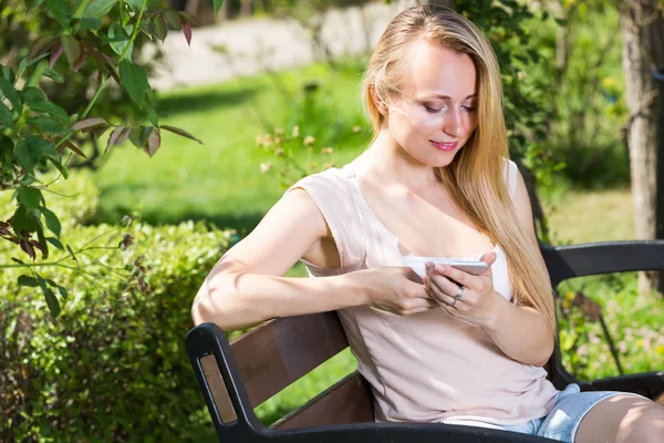 Junge Frau mit Smartphone im Garten — Stockfoto