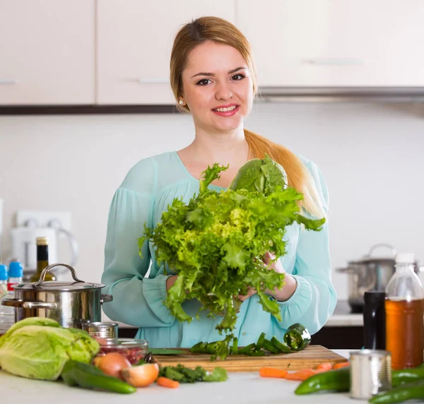 Junge Frau hackt Salat und Kräuter in Küche — Stockfoto