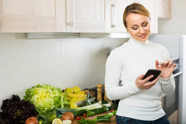 Dona de casa com telefone em casa kitche — Fotografia de Stock