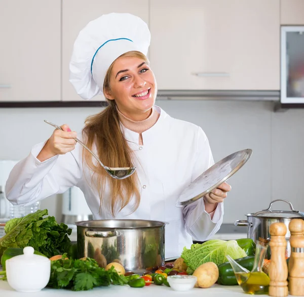 Mutlu kadın aşçı sebze hazırlıyor ve evde gülümsüyor. — Stok fotoğraf