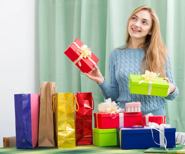 Blondine meisje zitten aan tafel met veel cadeautjes in dozen — Stockfoto