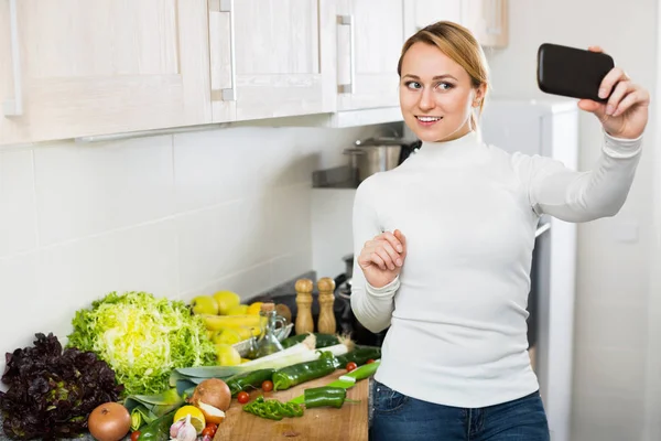 Alegre sorrindo dona de casa fazendo foto de si mesma — Fotografia de Stock