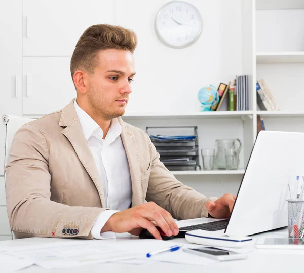 Jongeman met laptop op kantoor — Stockfoto