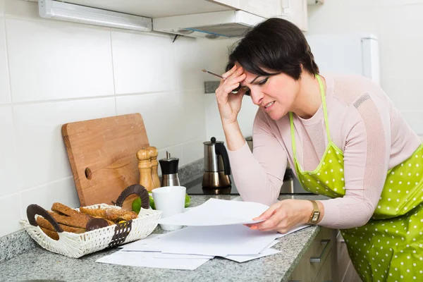 Triste femme au foyer d'âge moyen regardant à travers les factures — Photo