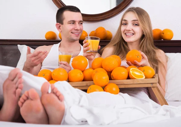 Uomo e fidanzata bere spremuto succo d'arancia a letto — Foto Stock