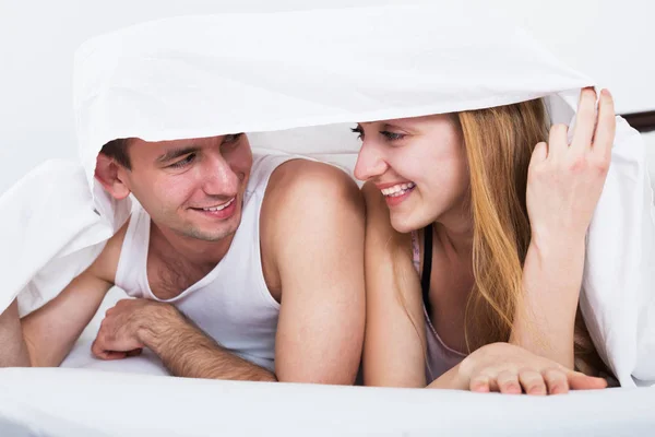 Loving couple hiding under cover — Stock Photo, Image