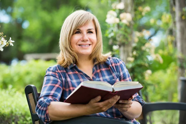 Zralé žena s knihou v zahradě — Stock fotografie