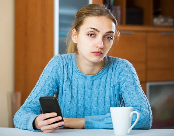 悲しい女性は 国内のインテリアで電話を待っています — ストック写真