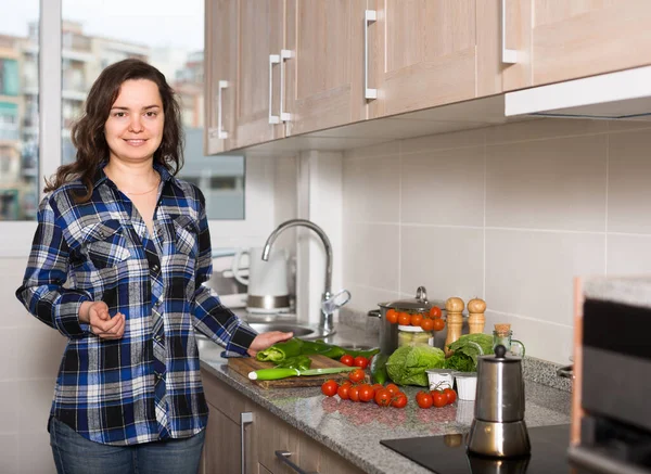 幸せな若いですブルネット女性準備野菜と笑顔でキッチン — ストック写真