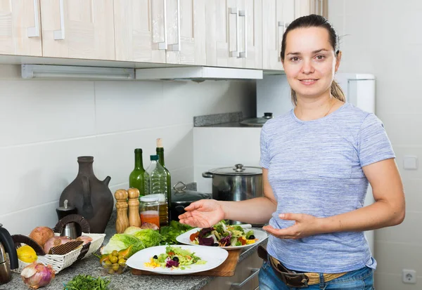 快乐的年轻女子站在厨房里 在室内准备绿色沙拉 — 图库照片