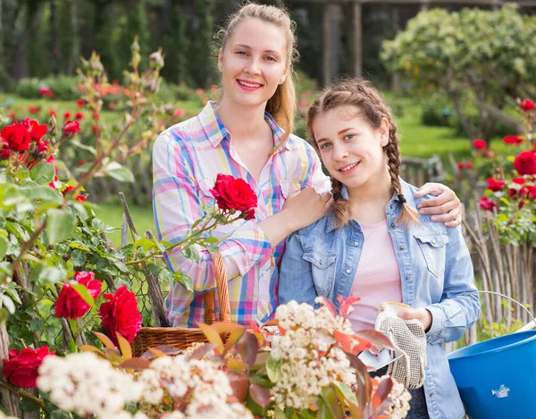 happy english woman and teen holding a basket and standing in the park of roses.